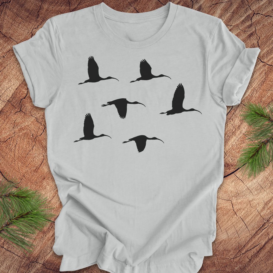Gray t-shirt with black ibis bird silhouettes on a wooden surface