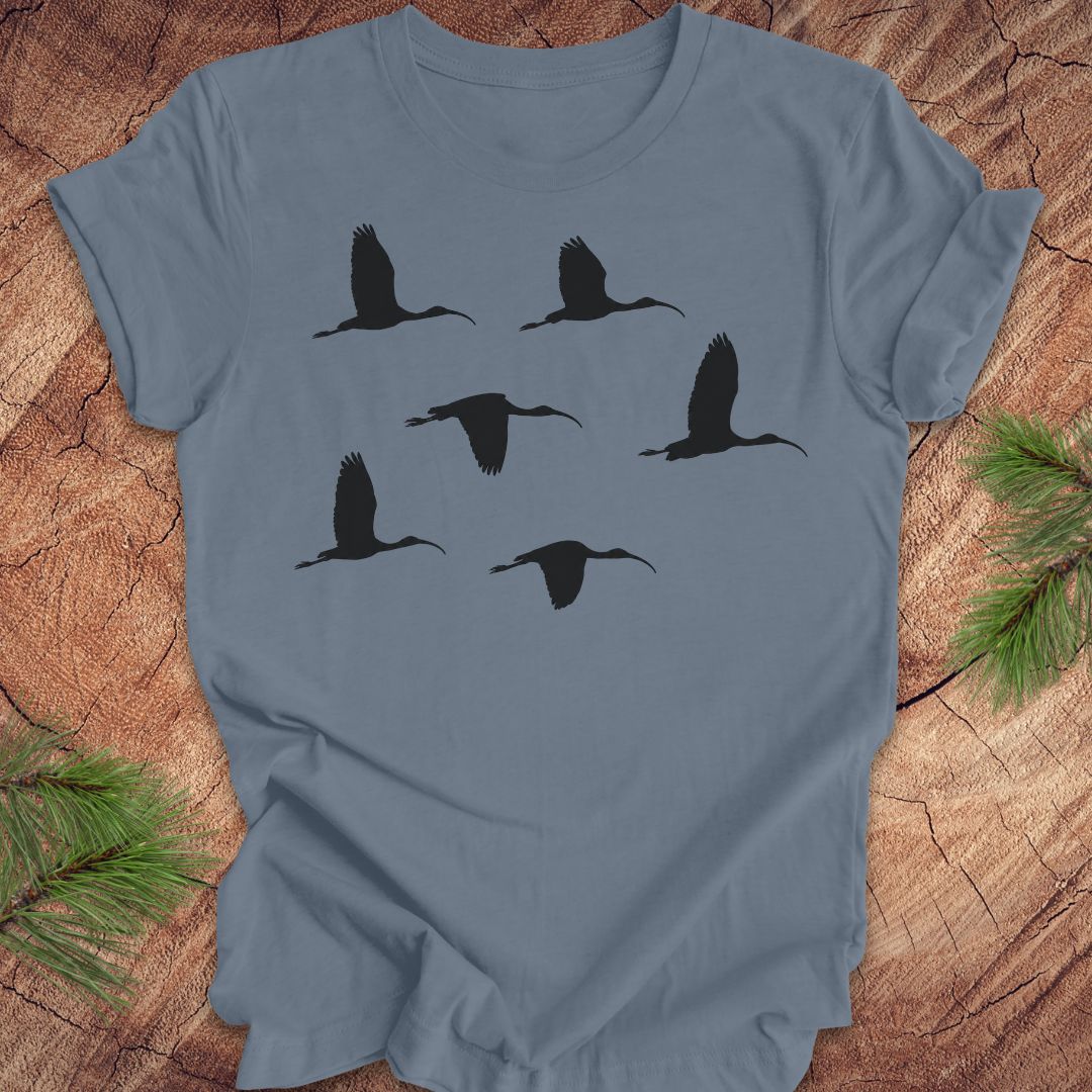 Blue t-shirt with black ibis bird silhouettes on a wooden surface