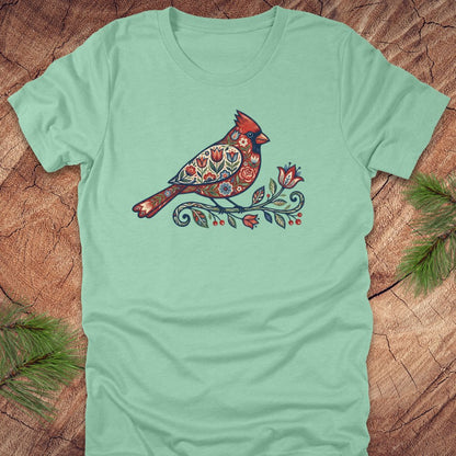 Mint green t-shirt with a colorful cardinal and flower design on a wooden surface