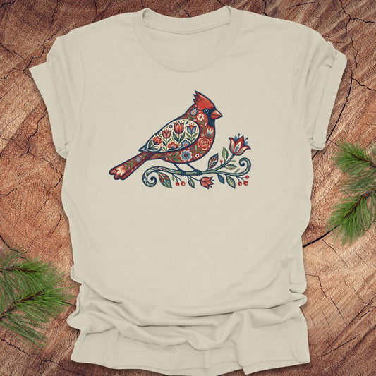 Beige t-shirt with a colorful cardinal and flower design on a wooden surface
