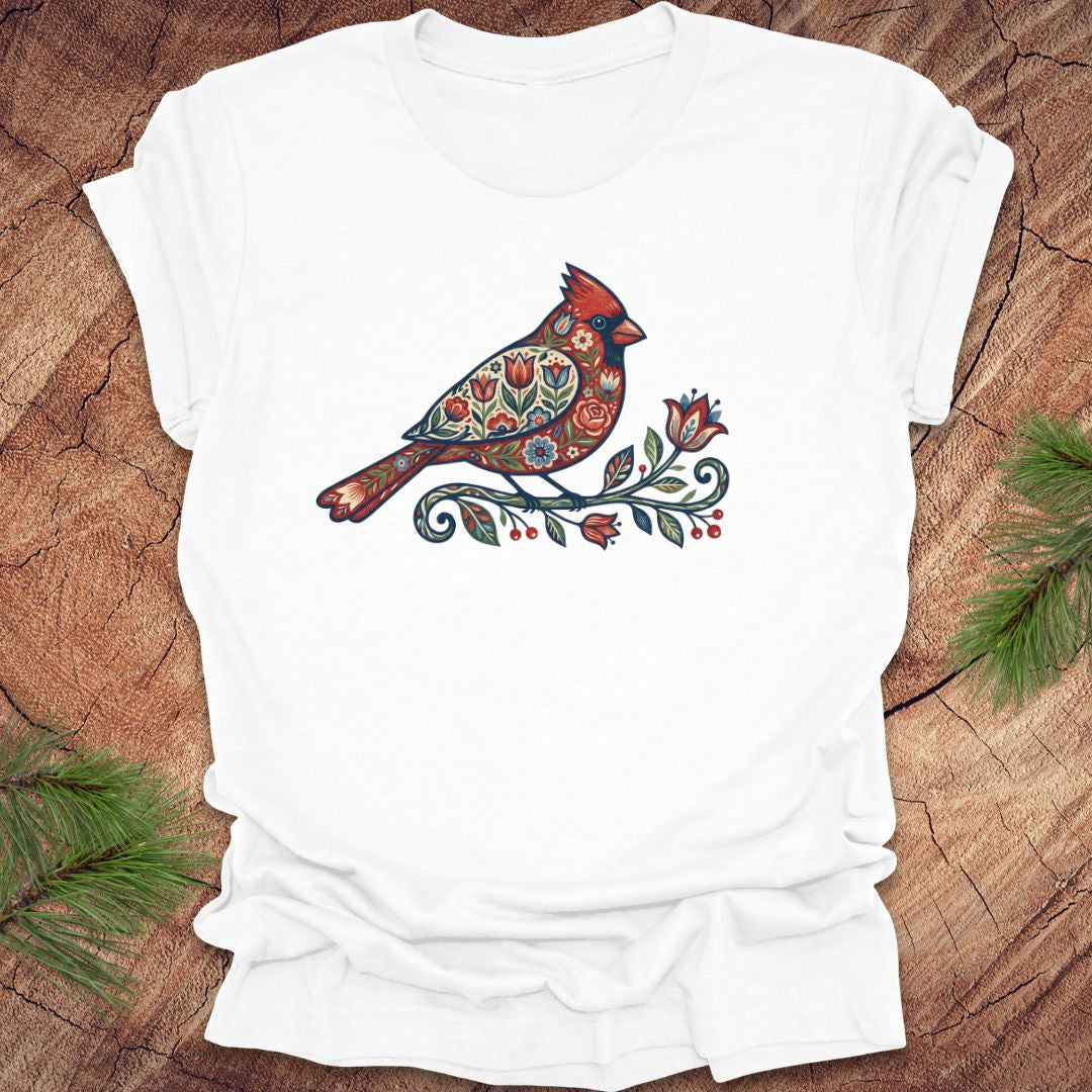 White t-shirt with a colorful cardinal and flower design on a wooden surface