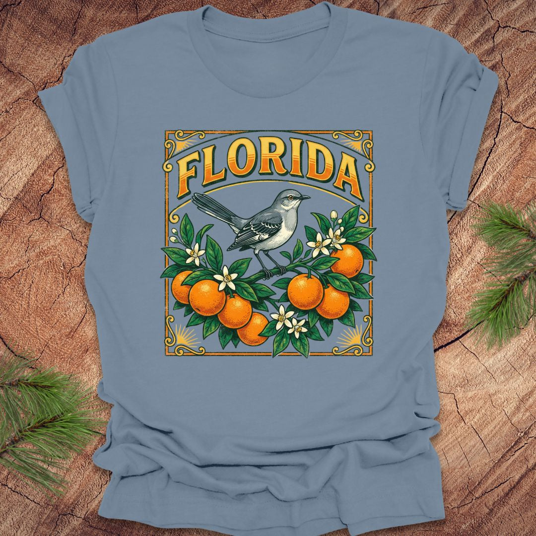 Steel blue t-shirt with a colorful Florida design with a mockingbird and oranges on a wood background.