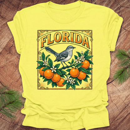Yellow t-shirt with a graphic of oranges, a bird, and the word 'Florida' on a wooden surface.