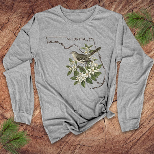 Gray long-sleeve shirt with Florida outline and mockingbird design on a wooden surface