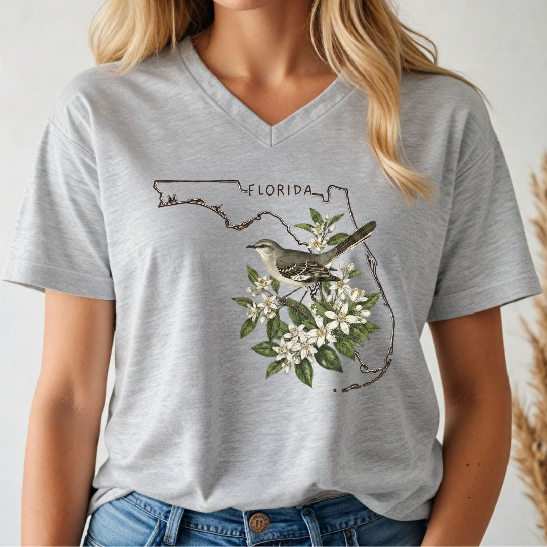 Person wearing a gray t-shirt with a Florida-themed design featuring a mockingbird and flowers.