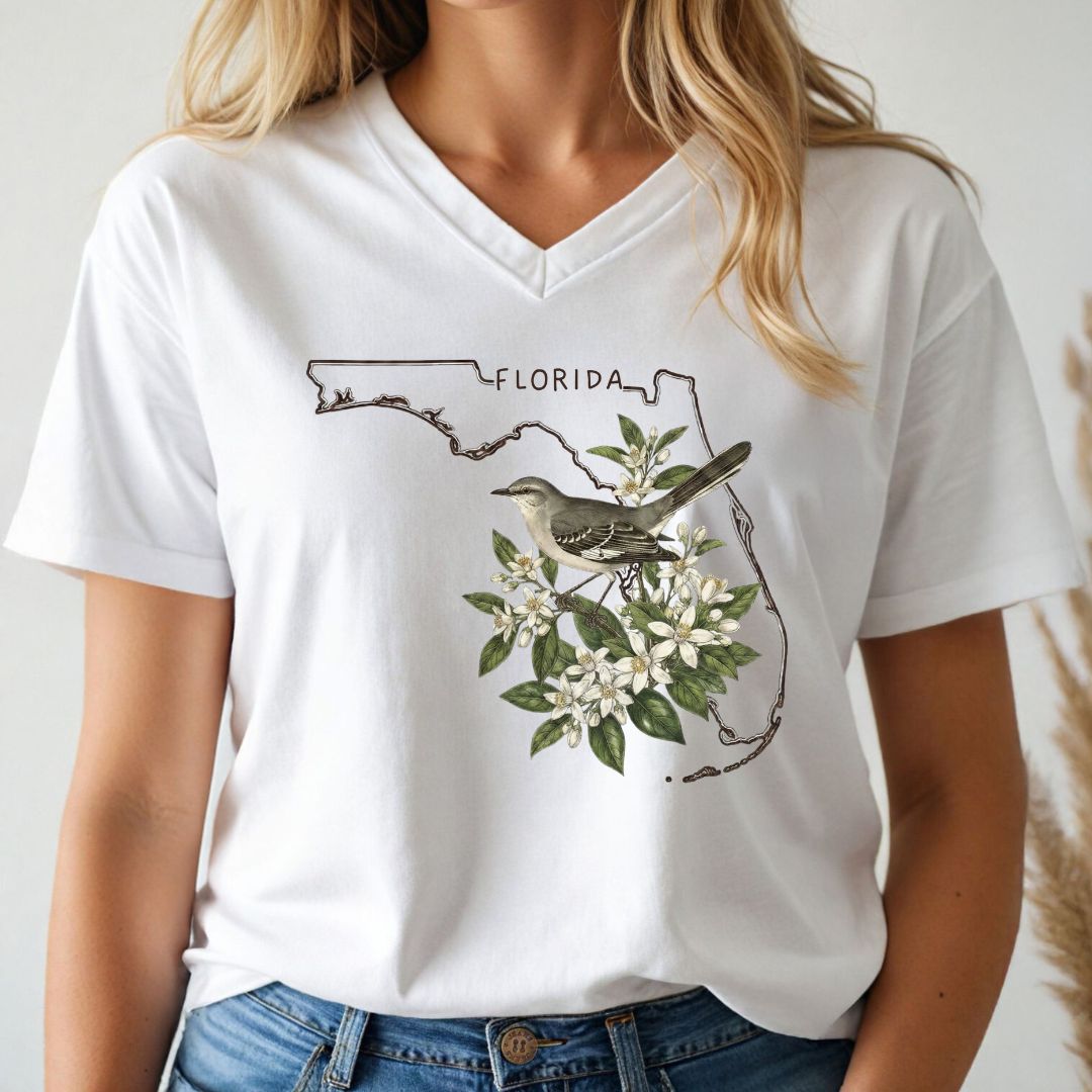 White t-shirt with Florida-themed design featuring a mockingbird and floral elements, worn by a person.