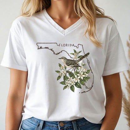 White t-shirt with Florida-themed design featuring a mockingbird and floral elements, worn by a person.
