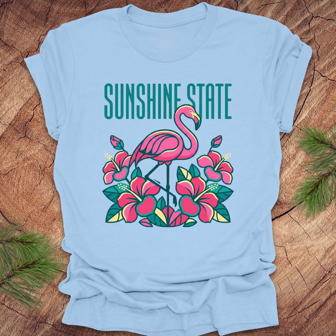 Light blue t-shirt with a flamingo and floral design on a wooden surface