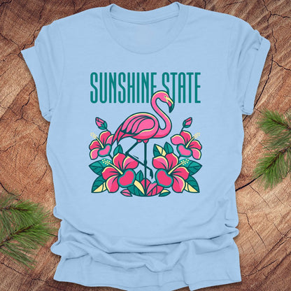 Light blue t-shirt with a flamingo and floral design on a wooden surface