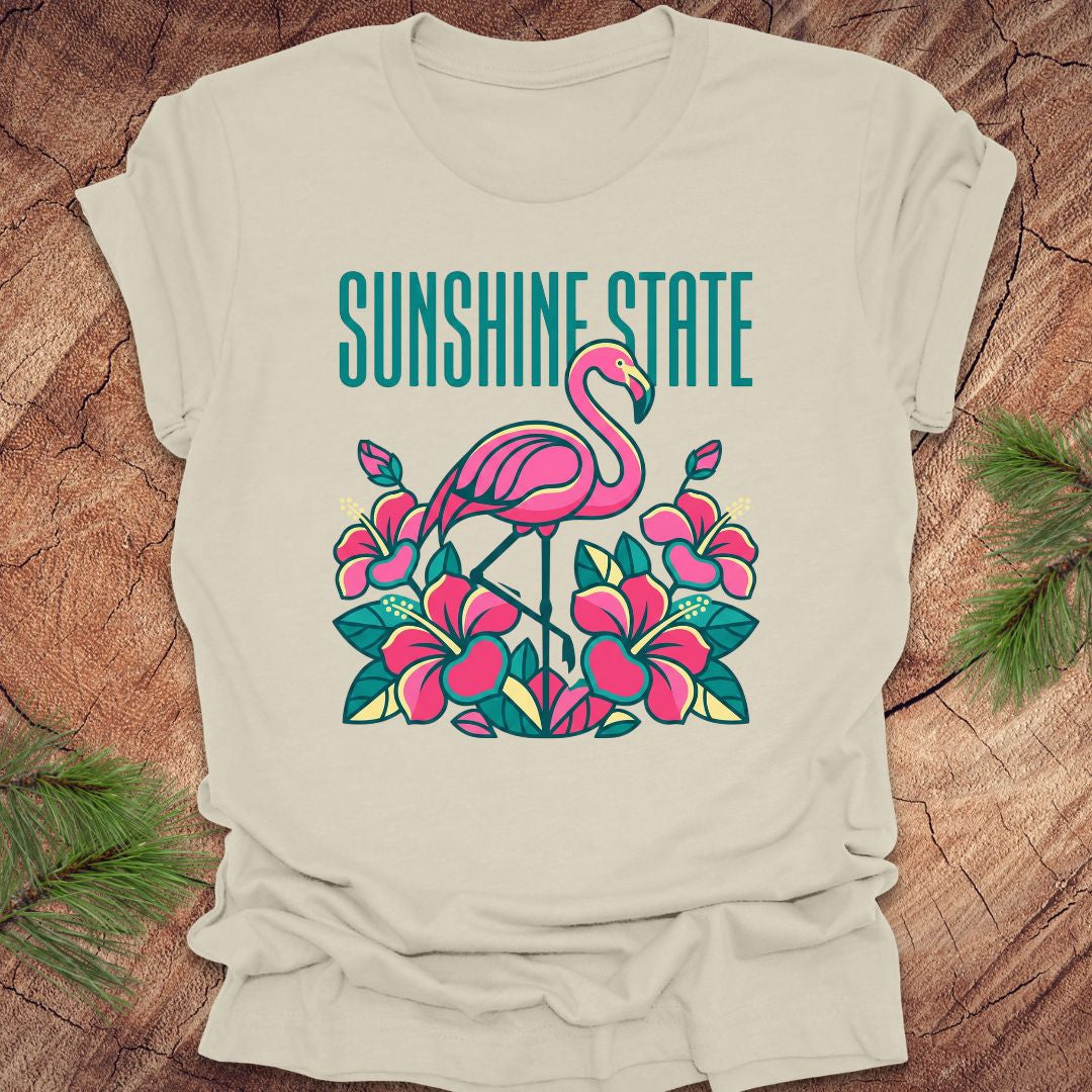 Beige t-shirt with a pink flamingo and floral design on a wooden surface