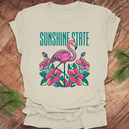 Beige t-shirt with a pink flamingo and floral design on a wooden surface