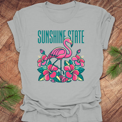 Gray t-shirt with a pink flamingo and floral design on a wooden surface