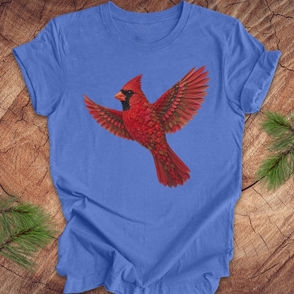 Blue t-shirt with a cardinal made of flowers on a wood background.
