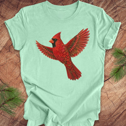 Mint green t-shirt with a cardinal made of flowers on a wood background.