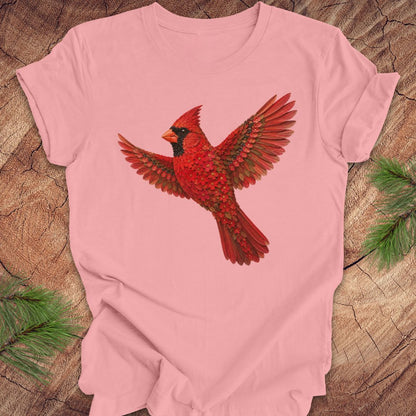Pink t-shirt with a cardinal made of flowers on a wood background.
