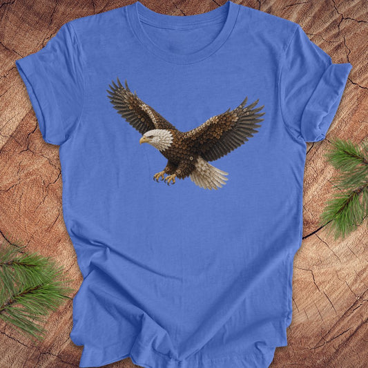 Blue t-shirt with an eagle made of flowers on a wood background.