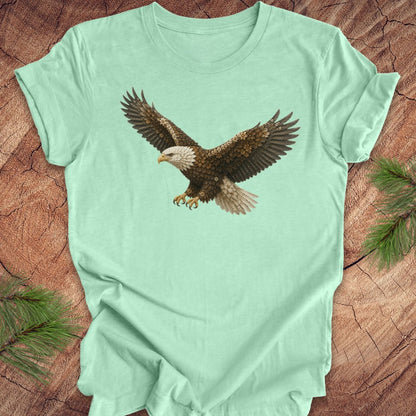 Mint green t-shirt with an eagle made of flowers on a wood background.