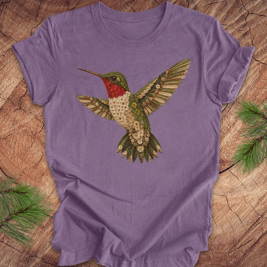 Purple t-shirt with a hummingbird and flower design on a wooden surface.