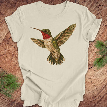 Beige t-shirt with a hummingbird and flower design on a wooden surface.