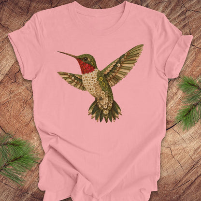  Pink t-shirt with a hummingbird and flower design on a wooden surface.