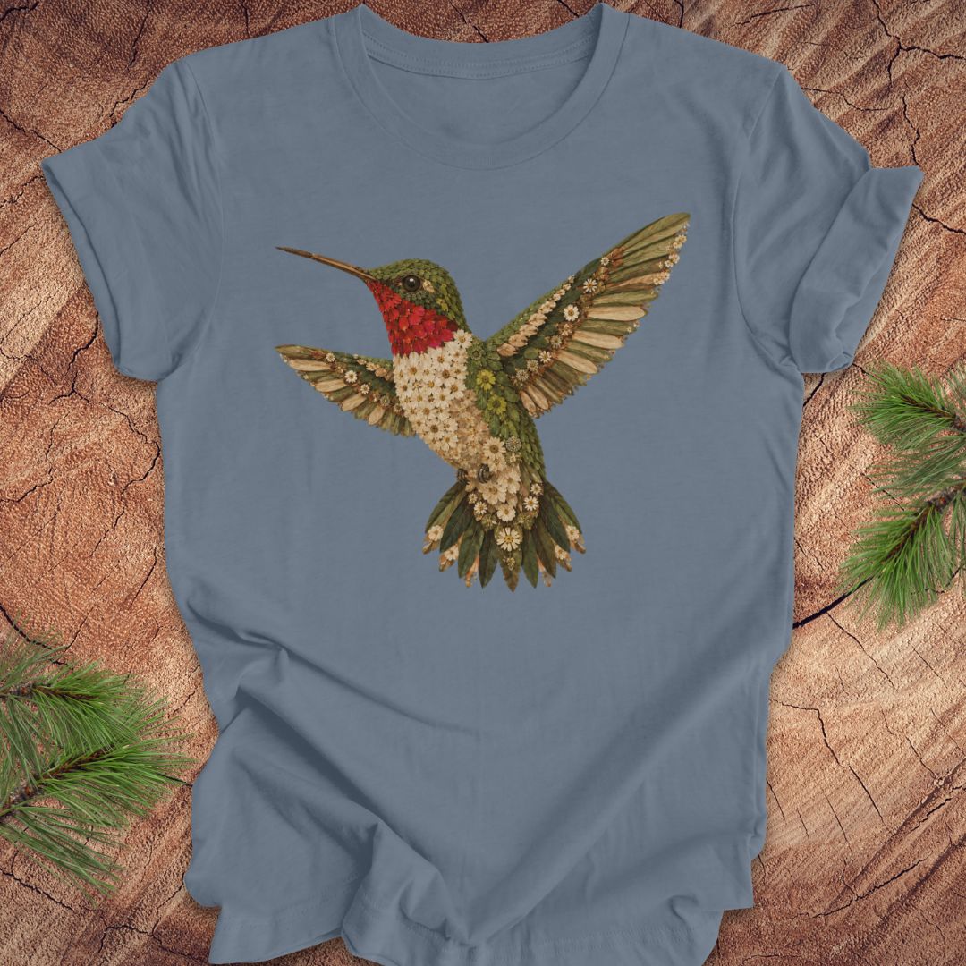 Blue t-shirt with a hummingbird and flower design on a wooden surface.