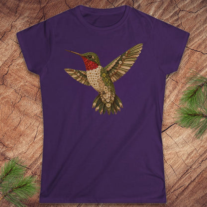 Purple t-shirt with a hummingbird made of flowers on a wood background.