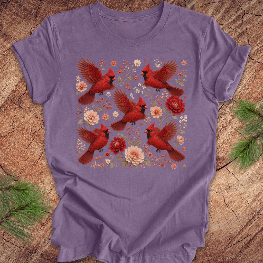 Purple t-shirt with cardinals and flowers on a wood background.