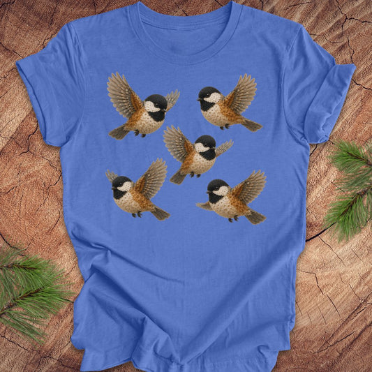 Blue t-shirt with 5 flower chickadees on a wood background.