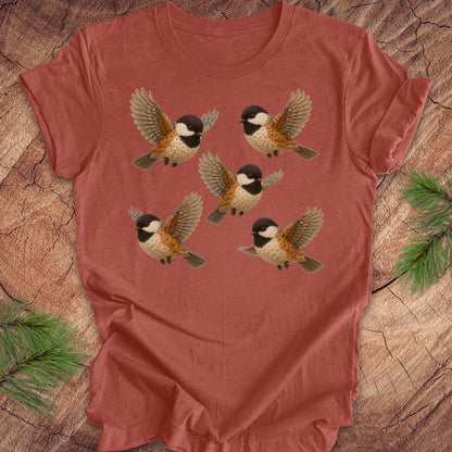 Clay colored t-shirt with 5 flower chickadees on a wood background.