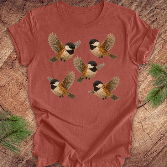 Clay colored t-shirt with 5 flower chickadees on a wood background.
