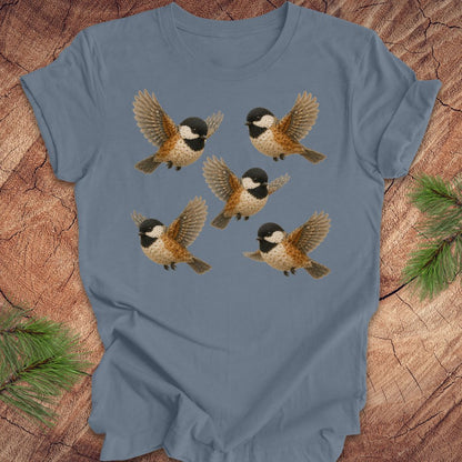 Blue t-shirt with 5 flower chickadees on a wood background.