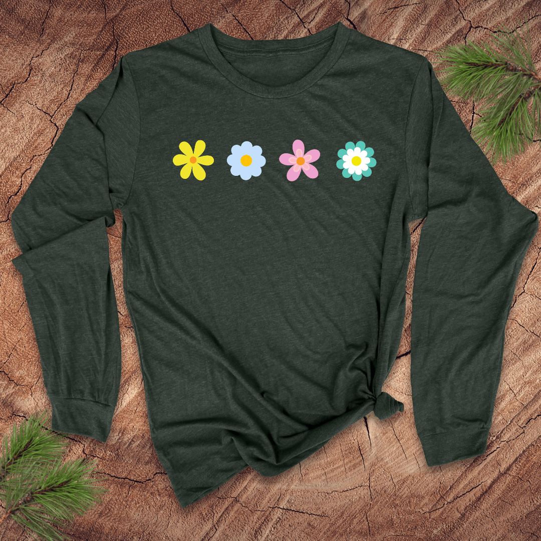 A green long-sleeve shirt with colorful flower designs on a wooden surface with pine branches
