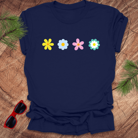 Navy blue t-shirt with colorful flower graphics on a wooden surface with sunglasses and greenery.