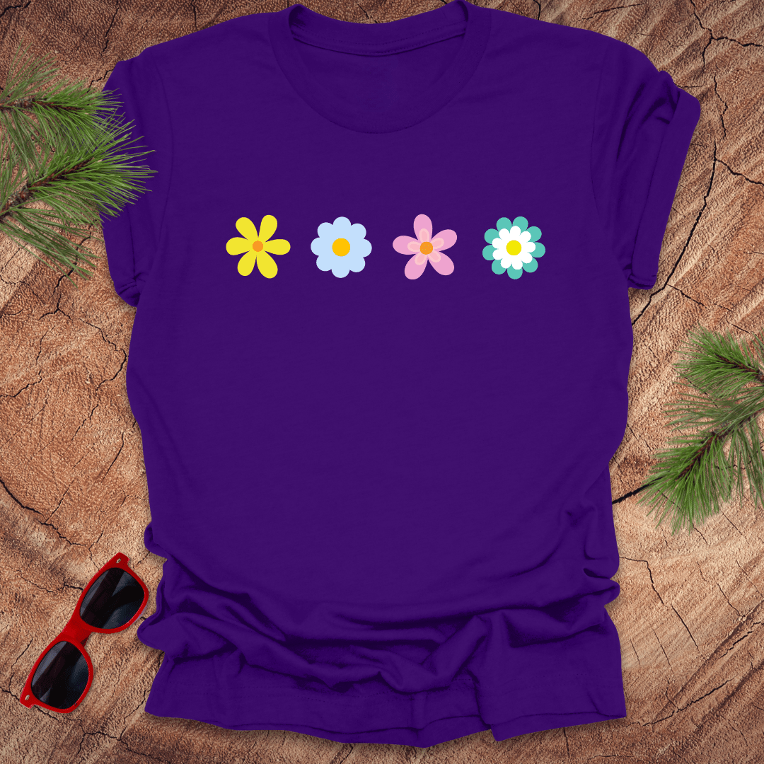 Purple t-shirt with colorful flower graphics on a wooden surface with sunglasses and greenery.