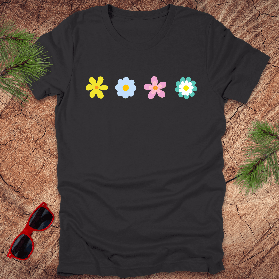 Black t-shirt with colorful flower design on a wooden surface with sunglasses and greenery.