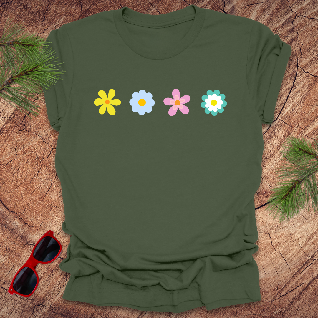 Green t-shirt with colorful flowers on a wooden surface with sunglasses and greenery.