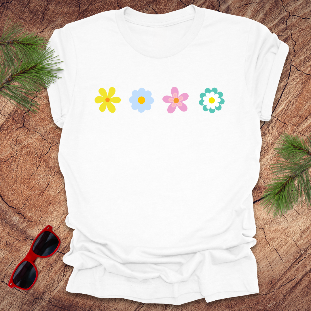 White t-shirt with colorful flower designs on a wooden surface with sunglasses and greenery.