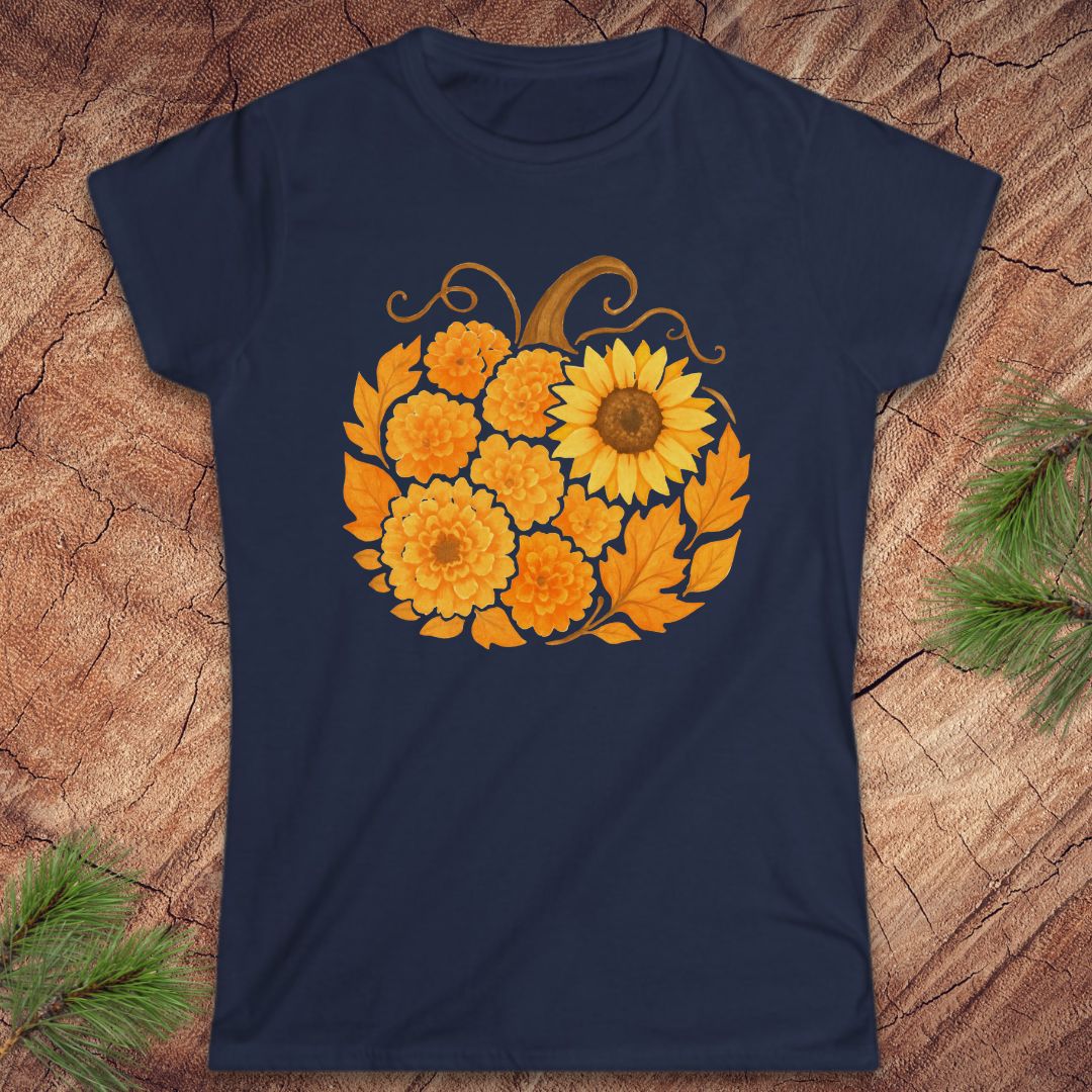 A navy blue short-sleeve t-shirt with a graphic of a pumpkin made from yellow sunflowers and orange marigolds, displayed flat on a rustic wood background with pine needles.