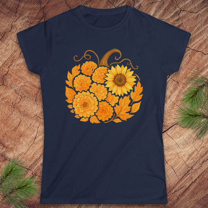 A navy blue short-sleeve t-shirt with a graphic of a pumpkin made from yellow sunflowers and orange marigolds, displayed flat on a rustic wood background with pine needles.