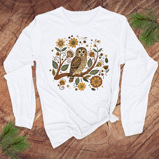White long-sleeve shirt with an owl and floral design on a wooden surface