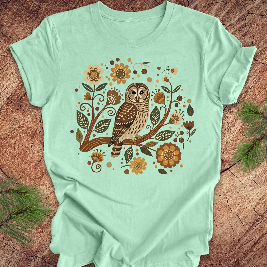 Mint green t-shirt with an owl and floral design on a wooden surface