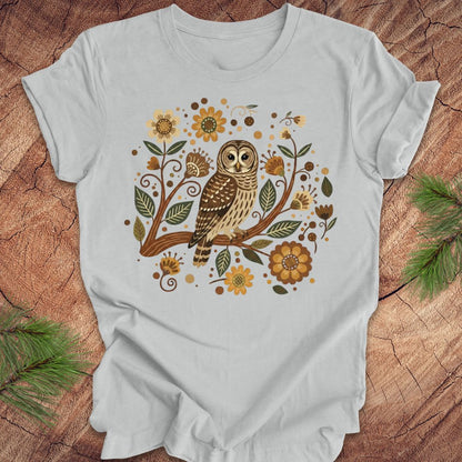 Gray t-shirt with an owl and floral design on a wooden surface