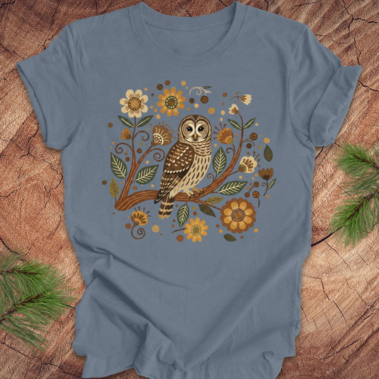 Blue t-shirt with an owl and floral design on a wooden surface