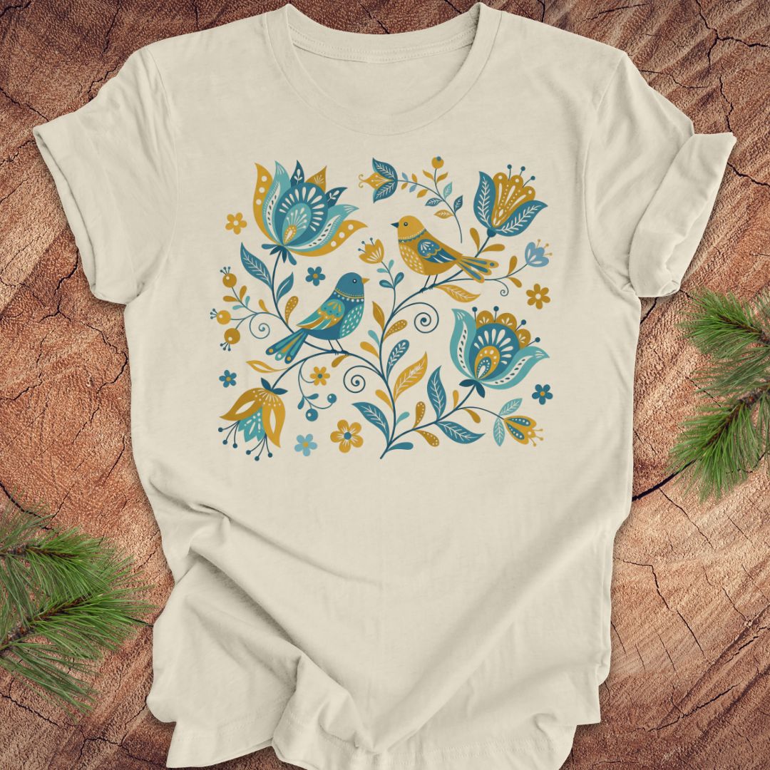 Beige t-shirt with floral and bird design on a wooden surface