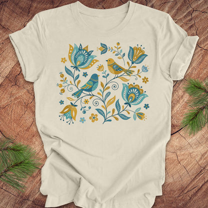 Beige t-shirt with floral and bird design on a wooden surface