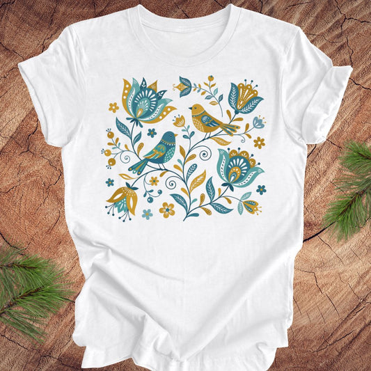 White t-shirt with floral and bird design on a wooden surface