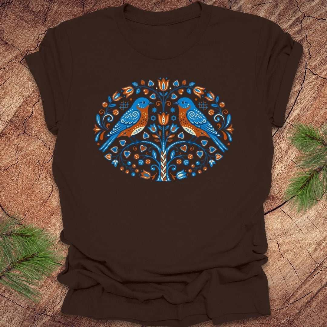 Brown t-shirt with a decorative design featuring two blue birds on a wooden surface.