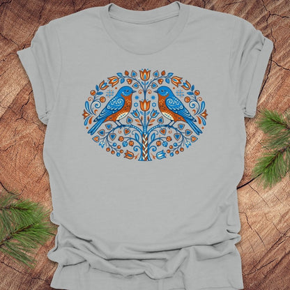 Gray t-shirt with blue bird design on a wooden surface