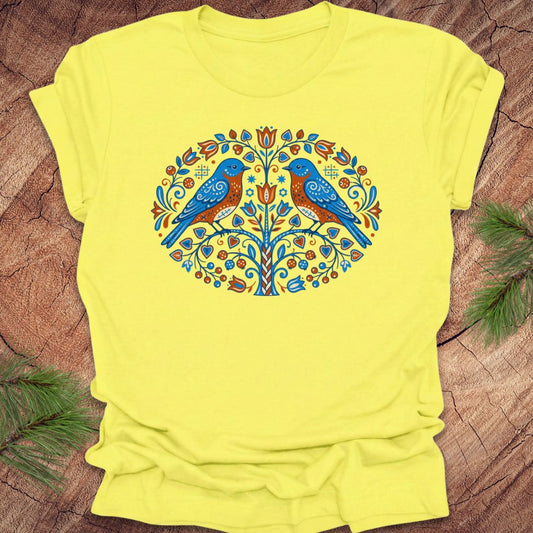 Yellow t-shirt with a colorful bird design on a wooden surface