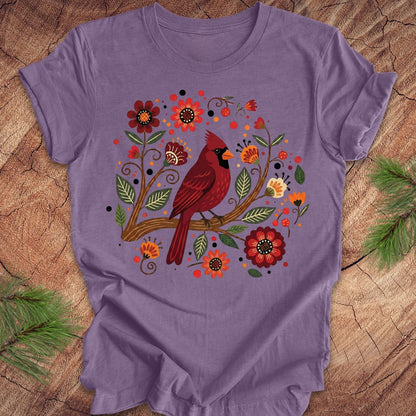 Purple t-shirt with a red cardinal and floral design on a wooden surface
